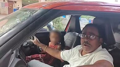 Man driving car with young girl in passenger seat, blurred face, in Hyderabad.