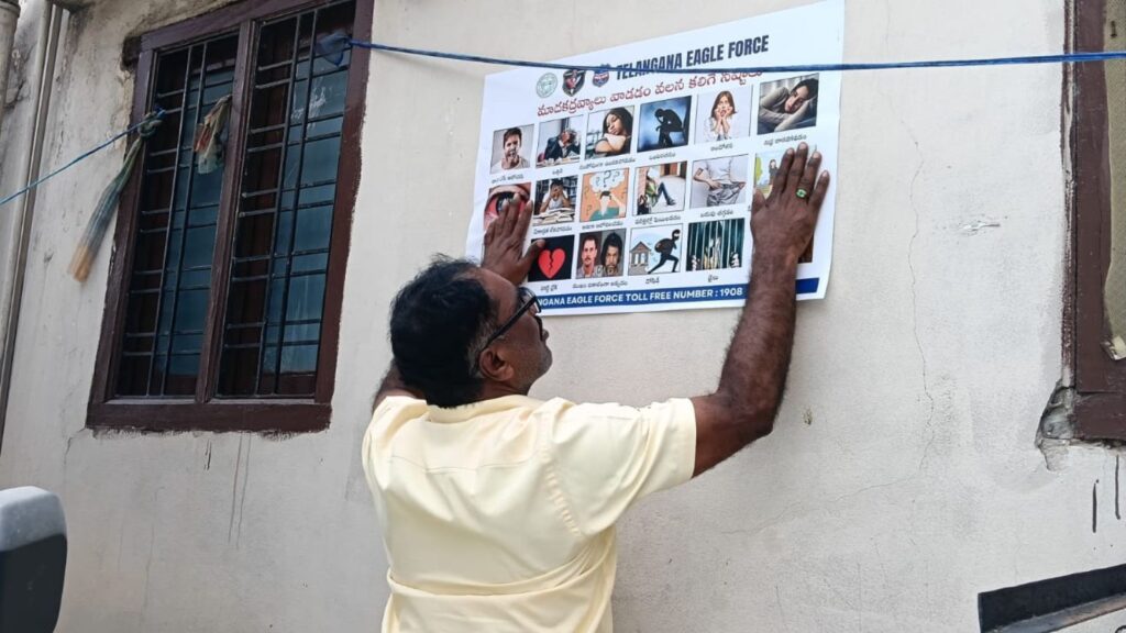 Man puts up anti-drug awareness poster on wall in Hyderabad.