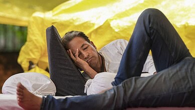 Man resting on a makeshift bed outdoors during a protest or event.