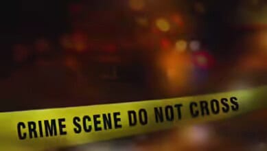 Crime scene tape with 'Crime Scene Do Not Cross' warning in focus, blurred background.