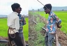 Two young boys in colourful shirts stand in a green paddy field in Madhya Pradesh.
