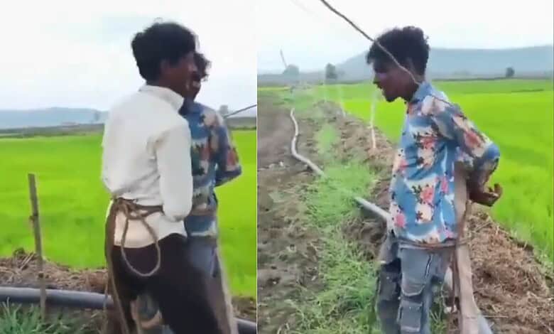 Two young boys in colourful shirts stand in a green paddy field in Madhya Pradesh.