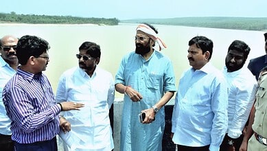 Group of men discussing near a water body during an irrigation project inspection.