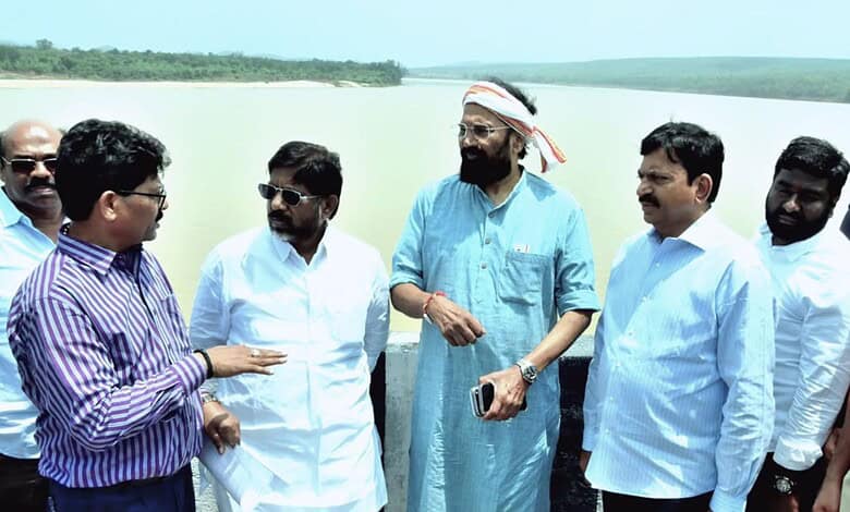 Group of men discussing near a water body during an irrigation project inspection.