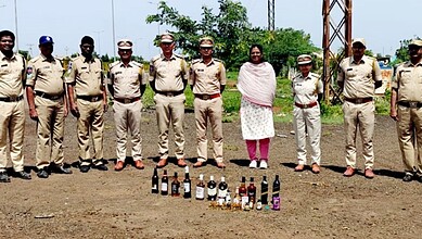 Telangana Excise officials with seized liquor bottles