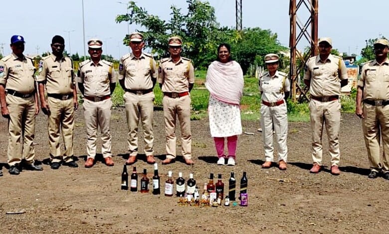 Telangana Excise officials with seized liquor bottles