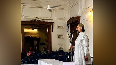 Asaduddin Owaisi speaking at a public event with a microphone in hand.