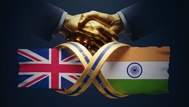 Handshake between two individuals with UK and India flags in the background.