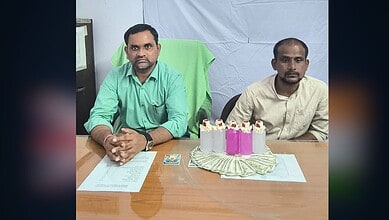 Two men sitting at a table with a birthday cake and money, in an indoor setting.