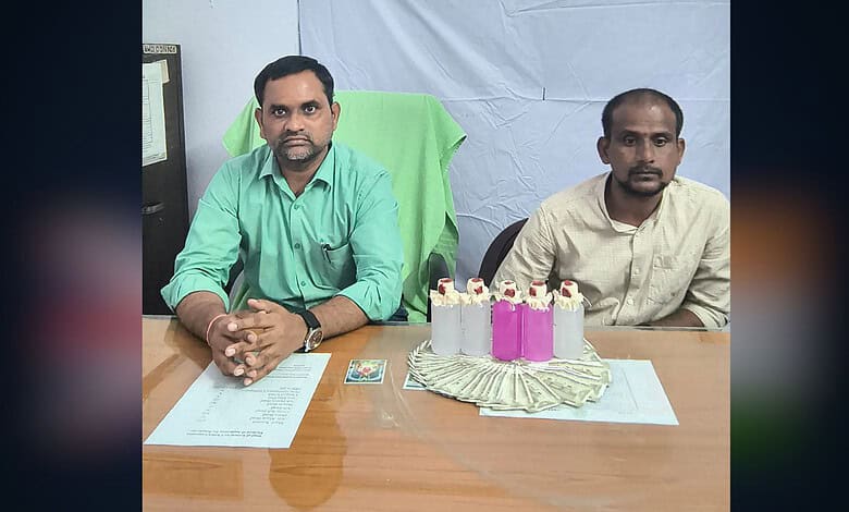 Two men sitting at a table with a birthday cake and money, in an indoor setting.