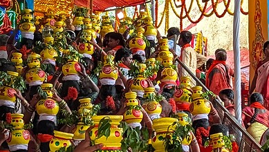 People participating in a traditional festival with decorated pots and vibrant attire.
