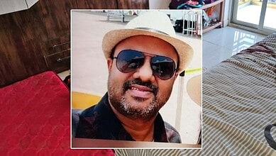 Man wearing sunglasses and a hat, smiling outdoors in bright sunlight.