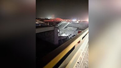Night view of a damaged bridge and water plant with emergency lights and construction activity.