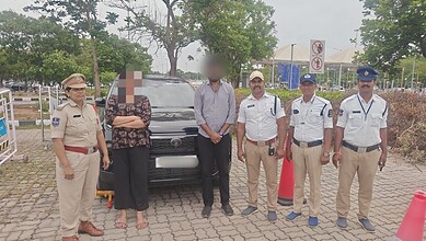 Group of police officers and civilians standing outdoors near a black vehicle in a parking lot.