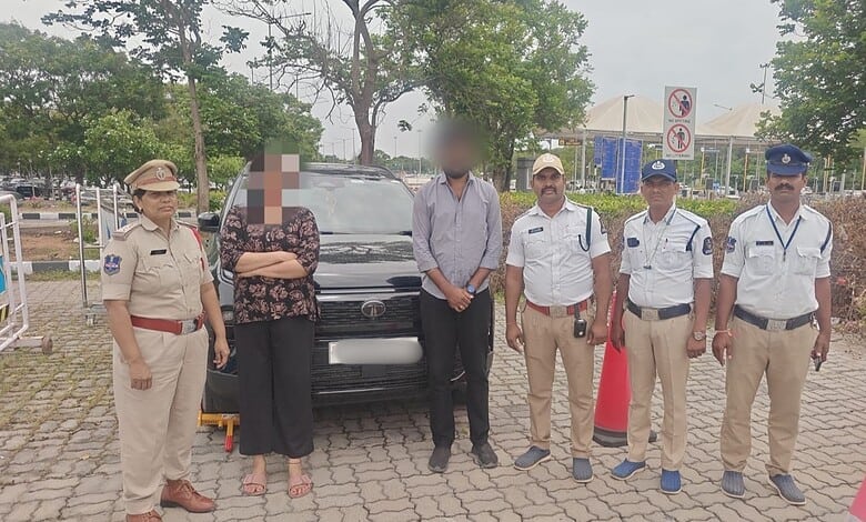 Group of police officers and civilians standing outdoors near a black vehicle in a parking lot.