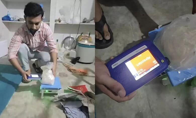 Person weighing a substance with a digital scale in a room, close-up of the scale display.