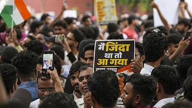 Protesters at Jantar Mantar hold signs during Chalo Sansad event in Delhi.