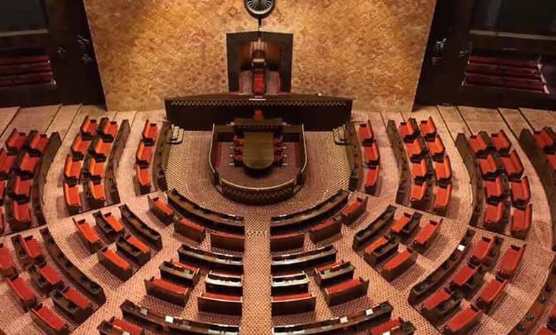 Empty Rajya Sabha chamber with seats and central podium in Parliament House, India.