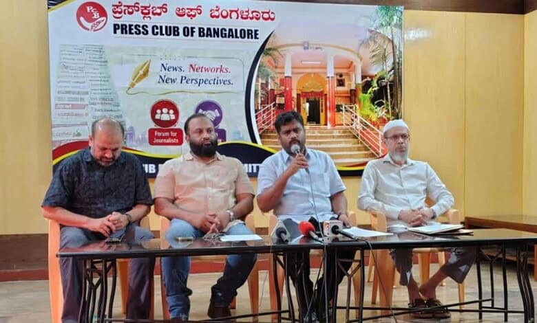 Four men seated at a press conference table with microphones in Bangalore.