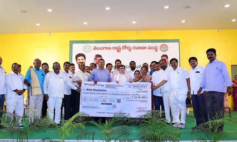 Group of men on stage holding a large cheque at a community event in Telangana.