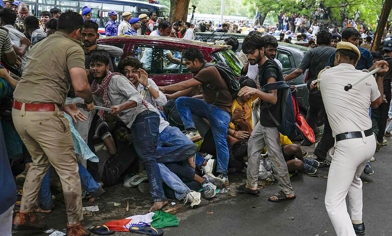 Clash between police and protesters causing chaos and injuries in a crowded street scene.