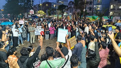Protest in Hyderabad with large crowd holding signs and banners during evening.