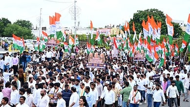 Large crowd of protesters with Indian flags marching during a political rally.