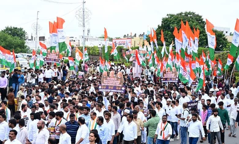 Large crowd of protesters with Indian flags marching during a political rally.