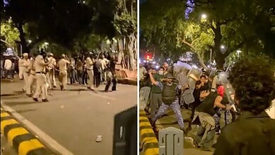 Police and protesters clash on a city street at night, with trees and streetlights visible.
