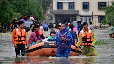 People use inflatable boats to eawde flood waters in Assam