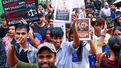 Protesters holding placards and taking photos during a demonstration in Mumbai.