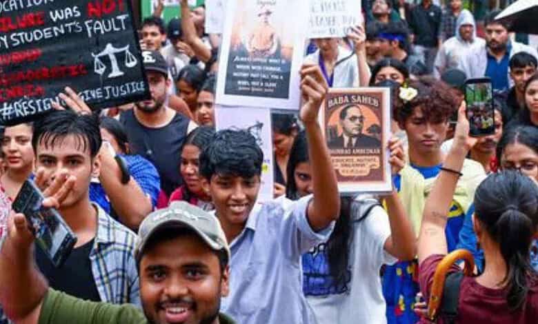 Protesters holding placards and taking photos during a demonstration in Mumbai.
