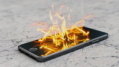 Mobile phone on ground with flames and fire emerging from the screen.
