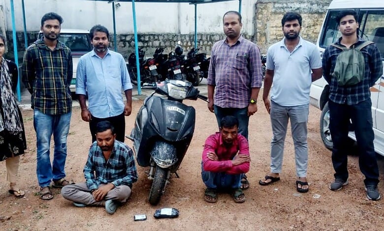 Group of nine men and two boys standing outdoors with a scooter and motorcycles in the background.