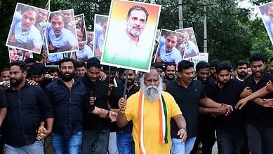 Protesters holding portraits of a political leader during a rally in a park.