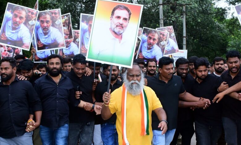 Protesters holding portraits of a political leader during a rally in a park.