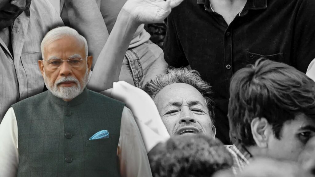 Indian Prime Minister Narendra Modi at a public event, raising his hand amidst a crowd.
