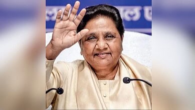 Mayawati waving during a public event, smiling and engaging with the audience.