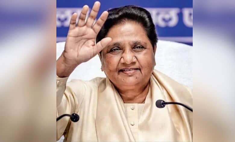 Mayawati waving during a public event, smiling and engaging with the audience.