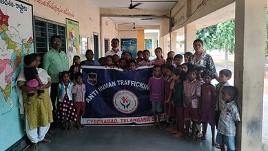 Group of children and adults holding a banner against human trafficking in Hyderabad, Telangana.