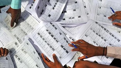 Voters' lists and ballot papers being reviewed and sorted by election officials.