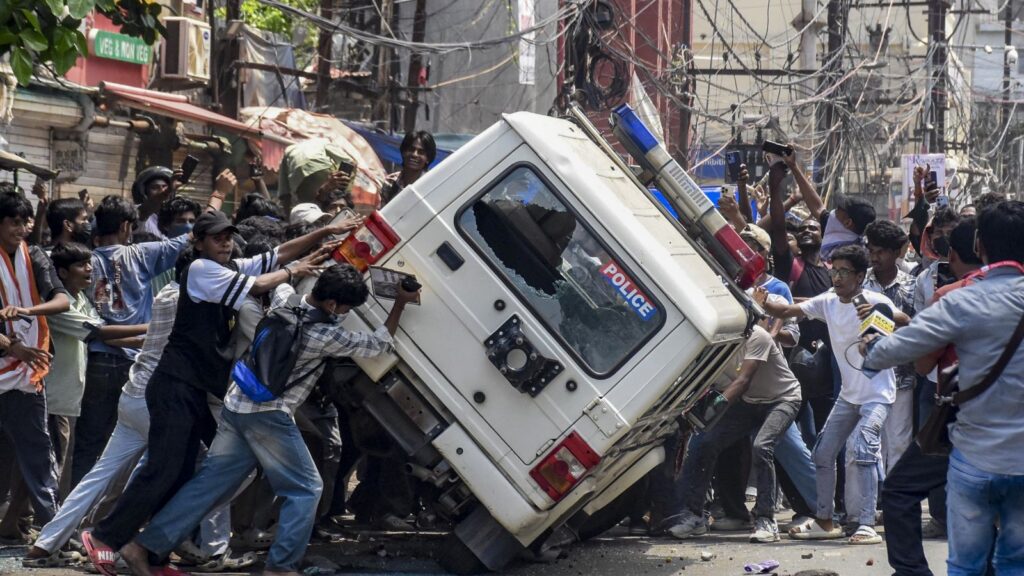 Protesters clash with police as a police vehicle is overturned during NEET bandh violence in Bihar.