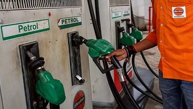 Person refueling vehicle with petrol at a petrol station, focus on fuel nozzle and pump.