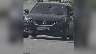 Black Suzuki car with damaged front bumper on the road during daytime.