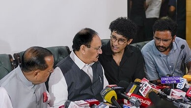 CJP with officials during a press conference, surrounded by microphones and media representatives.