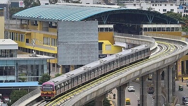 Modern metro train on elevated track at a busy urban station in India.