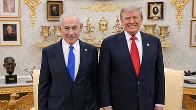 Donald Trump and Benjamin Netanyahu smiling during a meeting in a decorated room.