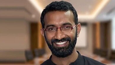 Portrait of a smiling man with glasses and beard in a professional setting.