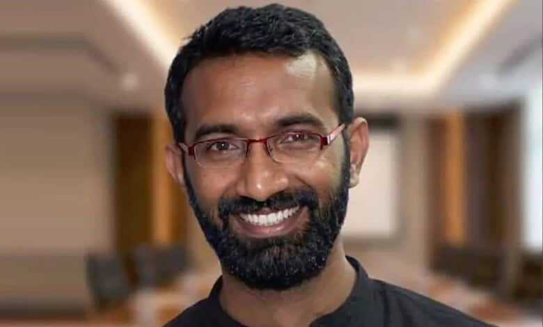 Portrait of a smiling man with glasses and beard in a professional setting.
