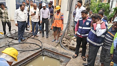 Officials inspect drainage work during Hyderabad rains, flood mitigation efforts in progress.